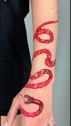 a woman's arm with red ink on it and a snake drawn on the wrist