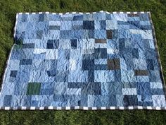 a patchwork quilt is laying on the ground in the grass with it's blue and green squares