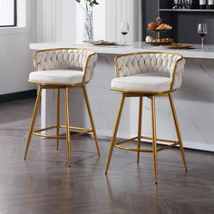 two white and gold bar stools in front of a marble counter with wine glasses on it