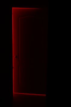 an open door in the dark with red light coming from it's center window