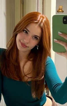 a woman taking a selfie with her cell phone in front of her face and wearing a green top