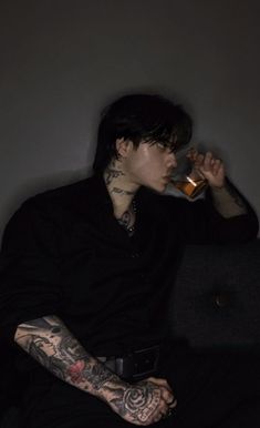 a man with tattoos drinking from a bottle