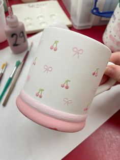 a person is holding a paper cup with cherries on it and pink trimmings