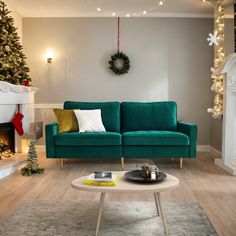 a living room decorated for christmas with green couches and white fireplace mantels