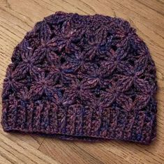 a purple crocheted hat sitting on top of a wooden floor