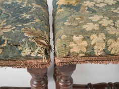 two antique wooden chairs with floral upholstered cushions and fringed ends, side by side