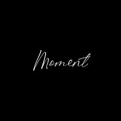 the word moment written in cursive writing on a black background with white ink