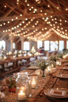 a long table is set with candles and flowers in mason jars on it, surrounded by string lights