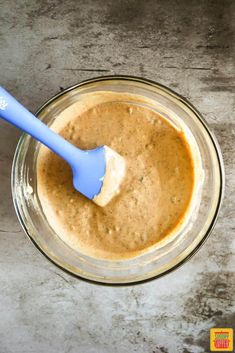 a glass bowl filled with batter and a blue spatula