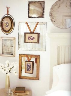 there are many framed pictures hanging on the wall next to a table with a vase