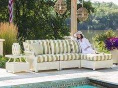 a woman sitting on top of a white couch next to a pool with flowers in it