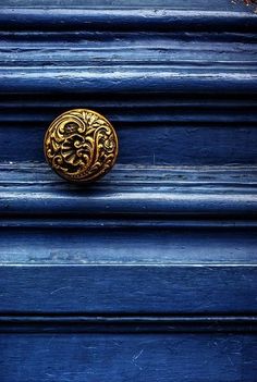 a blue door with a gold knob on it's side and an ornate design on the front