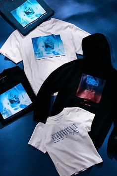 three t - shirts and an electronic device on a blue surface with the image of marilyn monroe