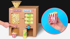 a hand is pointing at a popcorn vending machine with pop corn on the top