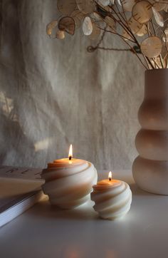 two candles sitting on top of a table next to a book