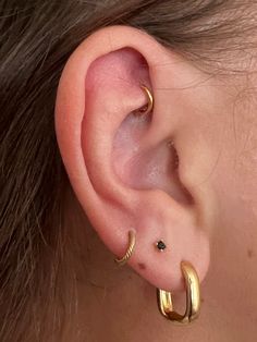 a close up of a person's ear with two gold hoops on it