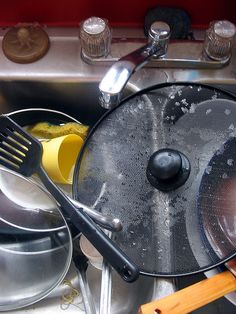 pots and pans are sitting in the sink with utensils on top of them