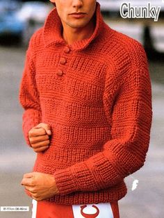 a young man wearing a red sweater and shorts with his hands in his pockets while standing on the street