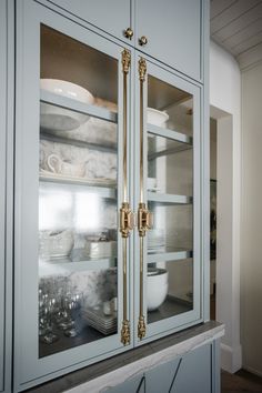 a kitchen cabinet with glass doors and gold handles