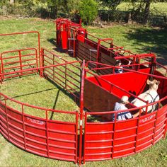 two men are riding in the back of red cattle pens