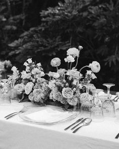 black and white photograph of table setting with flowers in vases, utensils and silverware