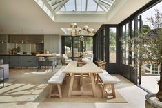 a dining room table with benches in front of an open kitchen and living room area