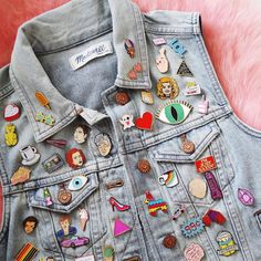 a denim jacket with lots of different pins on it and a pink furnishing