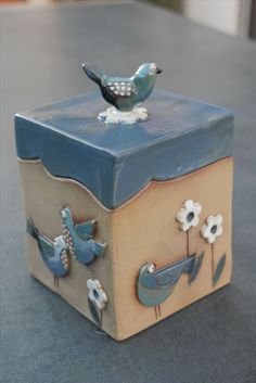 a blue bird sitting on top of a wooden box with flowers and birds painted on it