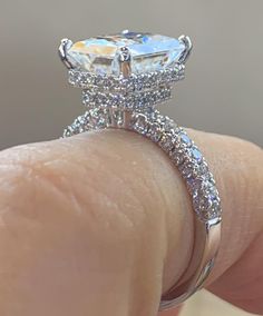 a woman's hand holding an engagement ring with a large diamond in the center