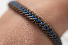 a close up of a person's arm with a blue and brown bracelet on it