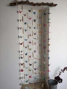 the curtain is decorated with colorful paper cranes on it's rod, and there are two vases next to it