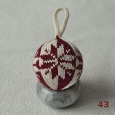 a red and white ornament sitting on top of a gray object with a rope