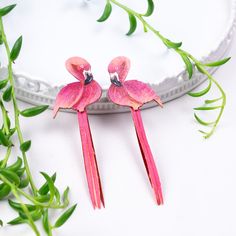 two pink birds are sitting on top of each other's heads in front of some green leaves