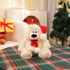 a white teddy bear sitting on top of a green and red table cloth next to a christmas tree