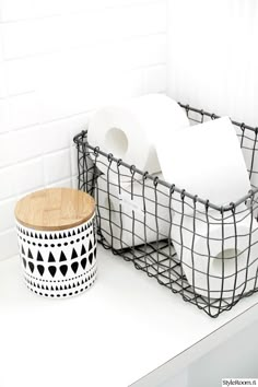 two black and white baskets sitting next to each other on top of a table with toilet paper