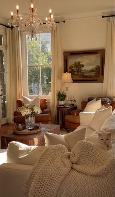 a living room filled with furniture and a chandelier hanging from the ceiling next to a window