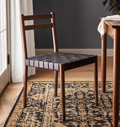 a wooden chair sitting on top of a rug next to a table with a potted plant