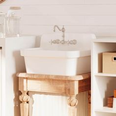 a white sink sitting on top of a wooden counter next to a shelf filled with boxes