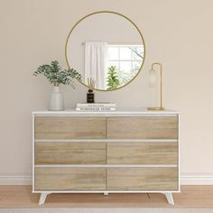 a white and wood dresser with a round mirror on it's sideboard next to a potted plant