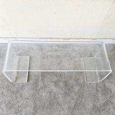 a clear acrylic shelf sitting on the floor