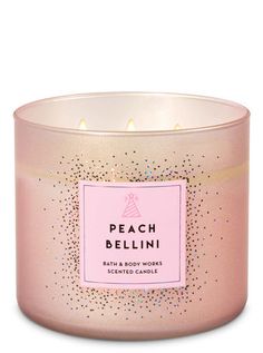 a pink candle that says peach bellini in front of a white background with sparkles