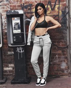 a woman standing next to a wall talking on a phone