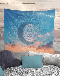 a large tapestry hanging on the wall above a bed with pillows and throw pillow cases