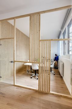 a room divider made out of wooden slats with people working in the background