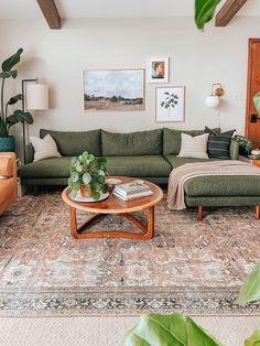 a living room with green couches and pictures on the wall above them, along with a coffee table