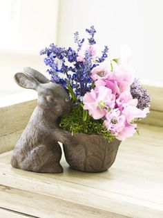 a small rabbit planter with flowers in it