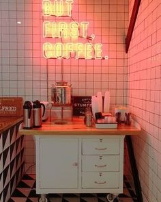 a pink neon sign above a counter in a room with black and white checkered flooring