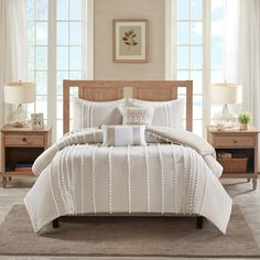 a bed with white comforter and pillows in a room