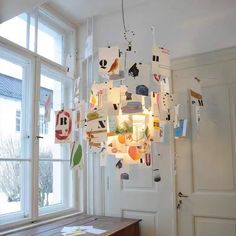 a light fixture hanging from the ceiling in a room with windows and pictures on it