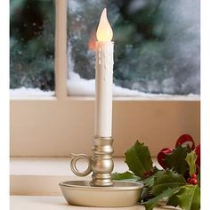 a lit candle sitting on top of a table next to a cup and saucer